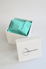 Load image into Gallery viewer, Ishtahfeetah Soapery hand-stamped gift box. White with turquoise tissue paper and white shred.