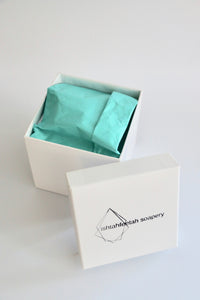 Ishtahfeetah Soapery hand-stamped gift box. White with turquoise tissue paper and white shred.